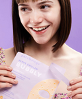 Woman holding a magazine with a purple cover against a purple background