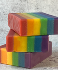 Stack of rainbow striped soap bars on a textured surface