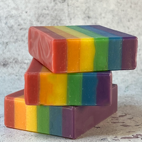 Stack of rainbow striped soap bars on a textured surface