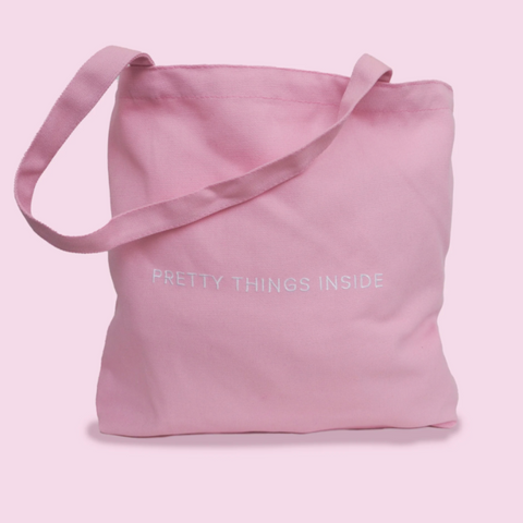 Pink tote bag with 'Pretty Things Inside' text on a light pink background