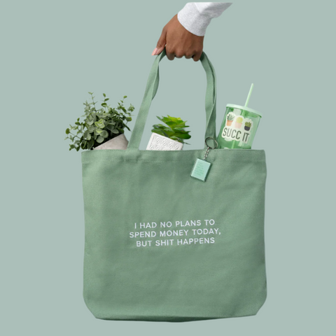 Green tote bag held by a hand with items inside against a light blue background