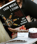 Woman reading a book titled 'From Where I Stand' with a candle and product on a table.