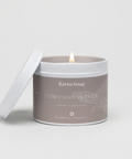 Candle in a gray container labeled 'Raven Song Cowichan Sweater' on a light gray background