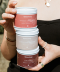 Person holding a stack of Raven Soap containers with a blurred background