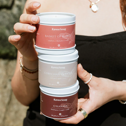 Person holding a stack of Raven Soap containers with a blurred background