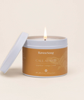 Candle in a tin with a visible brand label on a beige background