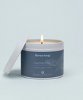 Candle in a tin with 'Raven Song' branding on a light gray background