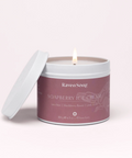 Candle in a tin labeled 'Raven Soap' with 'Wild Berries + Fireweed' on a light pink background