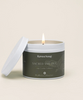 Candle in a container labeled 'Raven Song Sacred Smudge' on a light beige background
