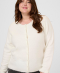 Woman wearing a white cardigan and dark jeans on a white background