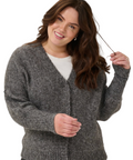 Woman wearing a gray cardigan holding a wand, with a white background