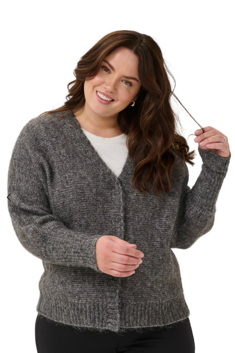 Woman wearing a gray cardigan holding a wand, with a white background