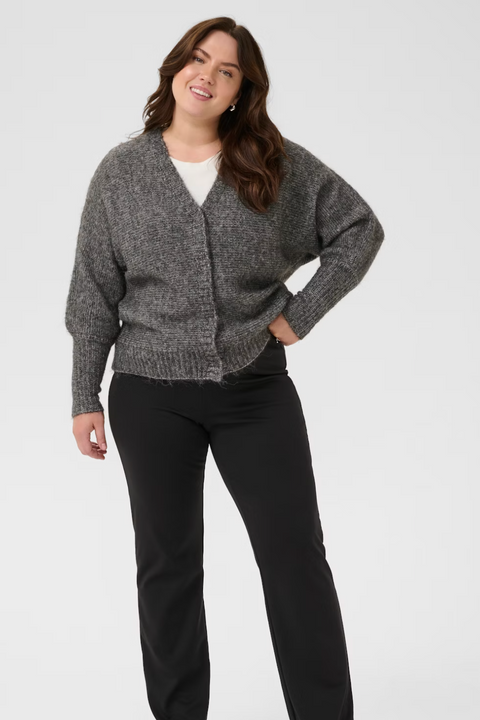 Woman wearing a gray cardigan and black pants on a white background