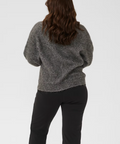 Person wearing a gray sweater and black pants on a white background