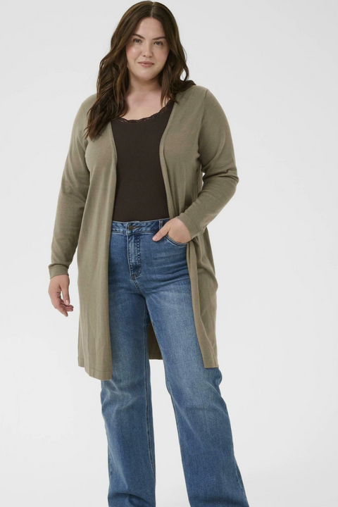 Woman wearing a green cardigan and blue jeans on a white background