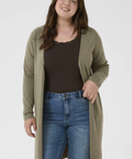Woman wearing a long olive green cardigan, black top, and blue jeans on a white background