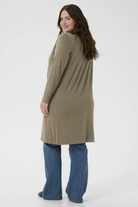 Woman wearing a long beige cardigan and blue jeans on a white background