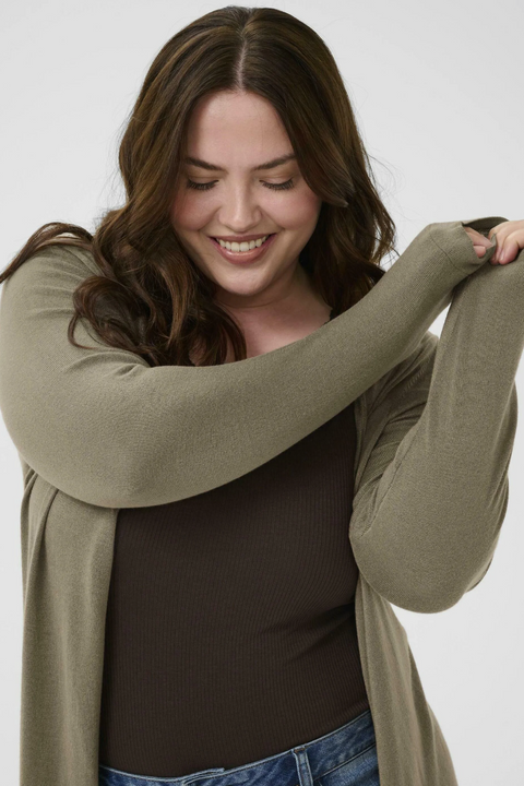 Woman wearing a green cardigan over a black top on a white background