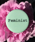 Button badge with 'Feminist' text on a pink flower