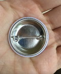 Metallic button badge held in a hand