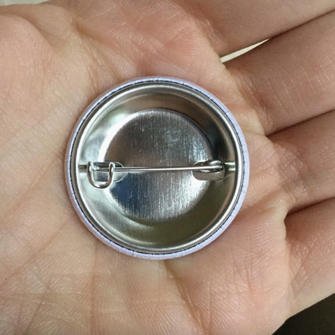 Metallic button badge held in a hand