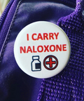 Button badge on a purple jacket with 'I CARRY NALOXONE' text and symbols.