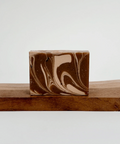 Marbled brown and beige soap bar on a wooden surface with a white background