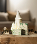 Decorative Christmas scene with a small tree and gift box on a wooden table, blurred background