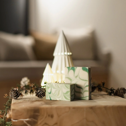Decorative Christmas scene with a small tree and gift box on a wooden table, blurred background