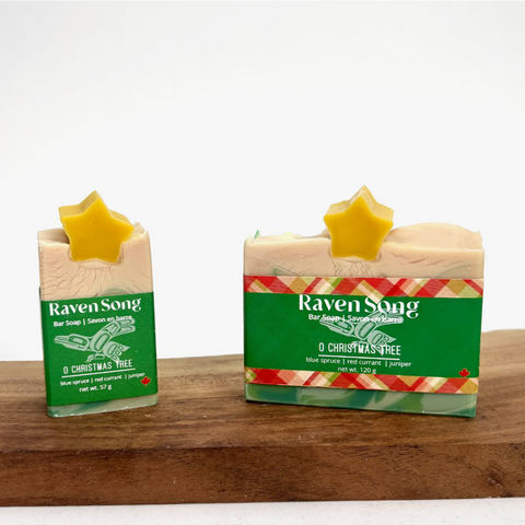 Two bars of soap with 'Raven Song' branding on a wooden surface.