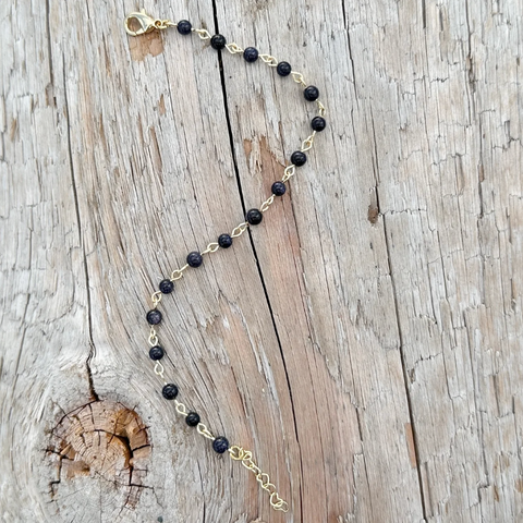 Necklace with black beads and gold chain on a wooden surface