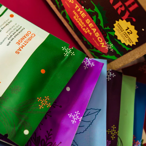 Tea packages with colorful labels on a red surface, displayed on a website page.
