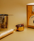 Tea-making set with tea infuser, scoop, and box on a beige background