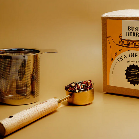Tea-making set with tea infuser, scoop, and box on a beige background