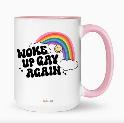 White mug with pink handle featuring a rainbow and text on a white background