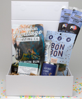 Gift box with snacks and a book titled 'Canadian Heritage Roasting Co.' on a colorful confetti background.