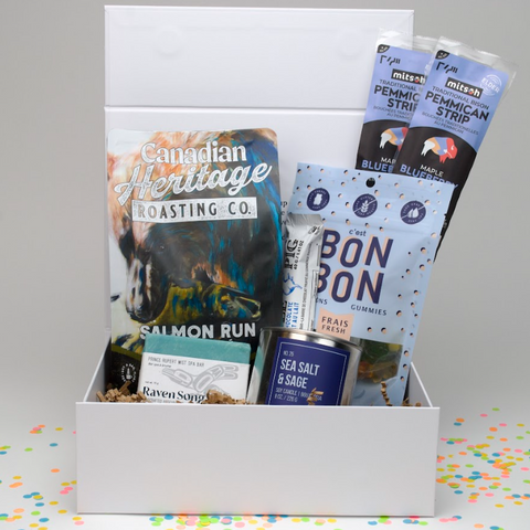 Gift box with snacks and a book titled 'Canadian Heritage Roasting Co.' on a colorful confetti background.