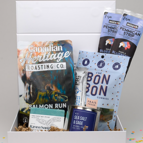 Assorted food items including a can of 'Canadian Heritage Roasting Co.' salmon run, 'Bon Bon' gummies, and 'Raven Song' tea in a box.