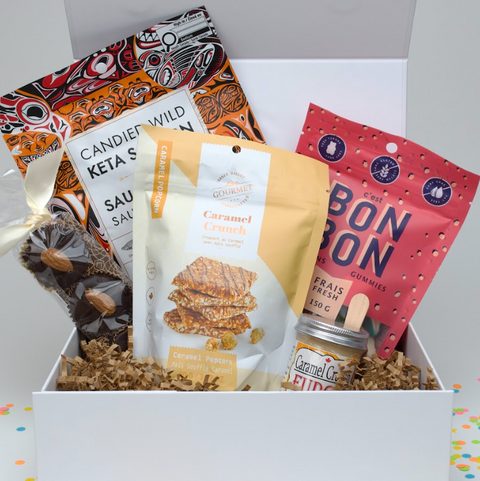 Assorted snacks and candies in a white box with colorful packaging.