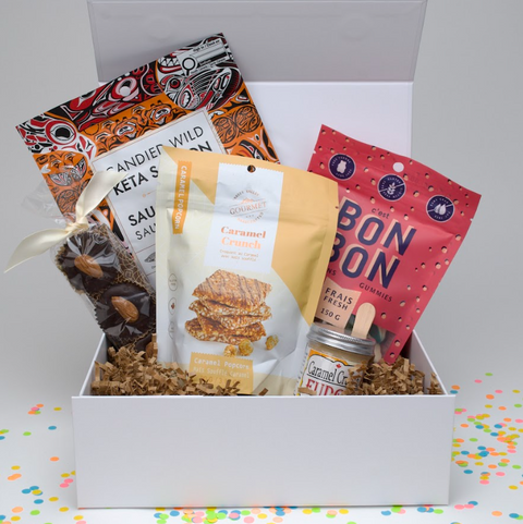 Assorted snacks in a white box with colorful confetti on a white background