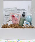 Gifting box with skincare products including a bottle, a bag, and a box on a white background.