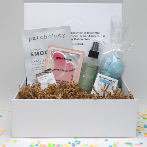 Gifting box with skincare products including a bottle, a bag, and a box on a white background.