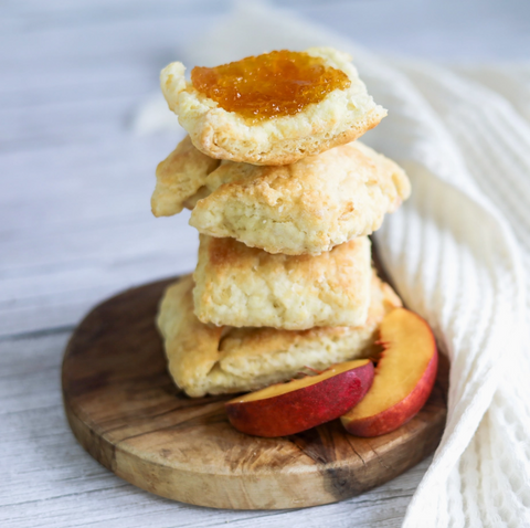 Stack of peach cobbler cookies on a wooden board with peaches