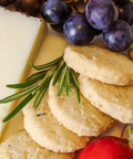 Platter with crackers, grapes, and a red pepper on a white surface