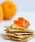 Stack of crackers with orange spread on a white background
