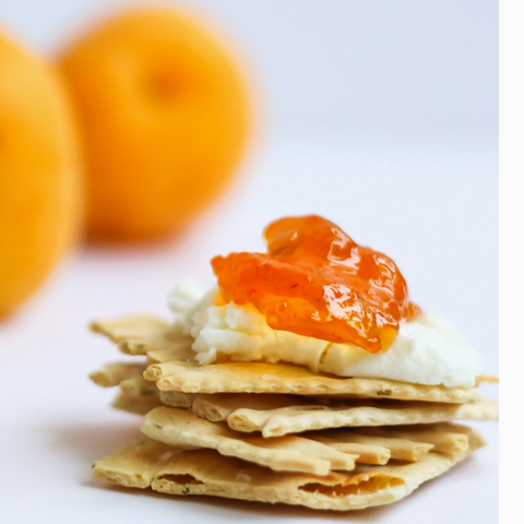 Stack of crackers with orange spread on a white background