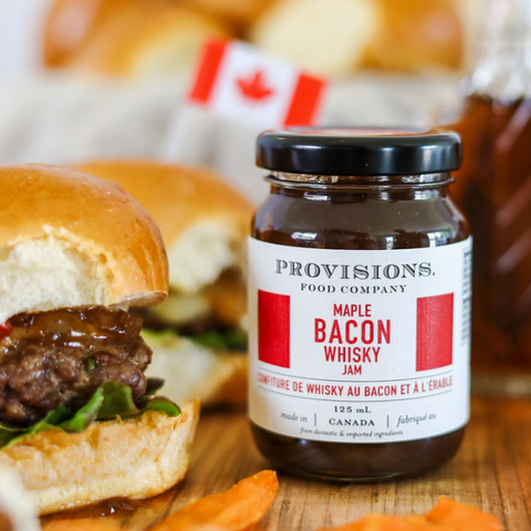 Bottle of Provisions Bacon Whisky with a burger on a wooden surface