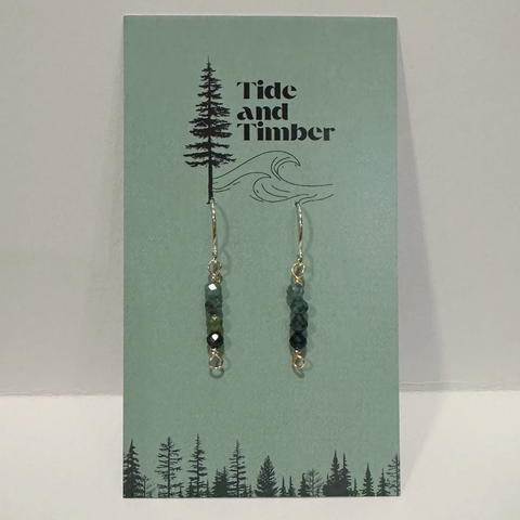 Pair of earrings on a 'Tide and Timber' branded card with nature-themed design.