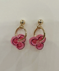 Pair of pink flower-shaped earrings with gold loops on a light beige background