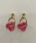 Pair of pink flower-shaped earrings with gold loops on a light gray background